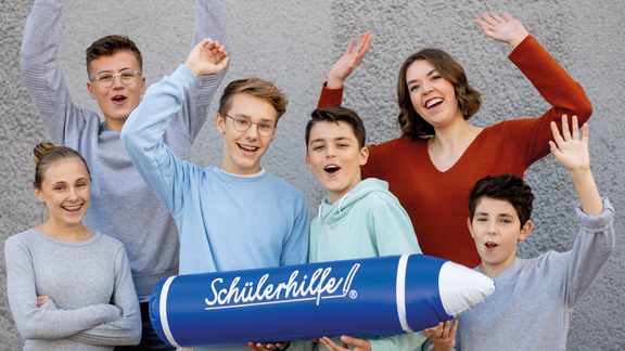 Sechs Kinder jubeln und halten einen Stift mit der Aufschrift "Schülerhilfe"