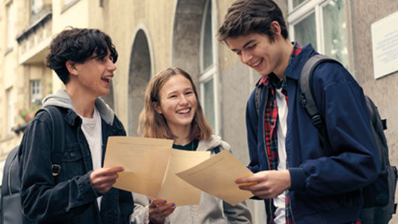 Das Pfingstferienangebot bei der Schülerhilfe 2 Jungs und ein Mädchen gucken sich ihre Zeugnisse an.