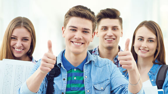 Mit der Schulstartaktion der Schülerhilfe 10 gratis Nachhilfestunden* sichern 2 Mädchen und 1 Junge im Hintergrund, 1 Junge im Vordergrund hält beide Daumen hoch